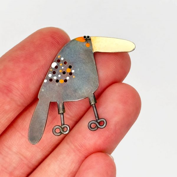 oxidized silver bird pin with gold beak, circle cut outs and orange and white spots